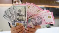 Nilai_Tukar_Rupiah51 Seorang pedagang valuta asing memamerkan lembaran uang rupiah dan dolar AS. (Foto Istimewa)