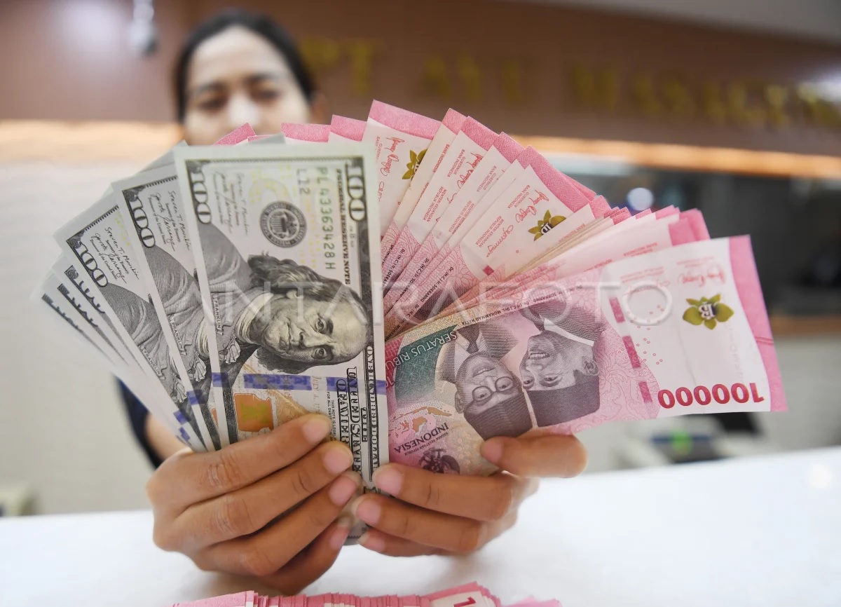Seorang pedagang valuta asing memamerkan lembaran uang rupiah dan dolar AS. (Foto Istimewa)